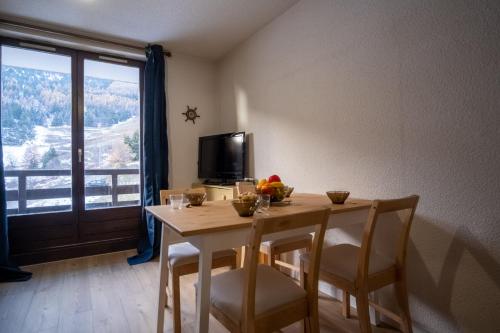 jadalnia ze stołem, krzesłami i telewizorem w obiekcie Charming studio with beautiful view - Huez - Welkeys w mieście LʼHuez