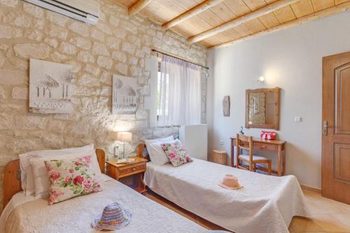 een slaapkamer met 2 bedden en een stenen muur bij Villa Hara Faragi by Villa Plus in Giannoudi