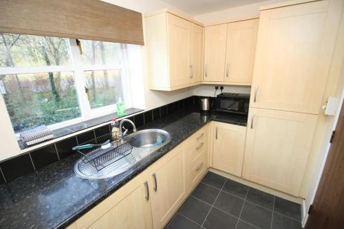 a kitchen with white cabinets and a sink and a window at Modern 2 bed flat on marina development! in Saint Peters
