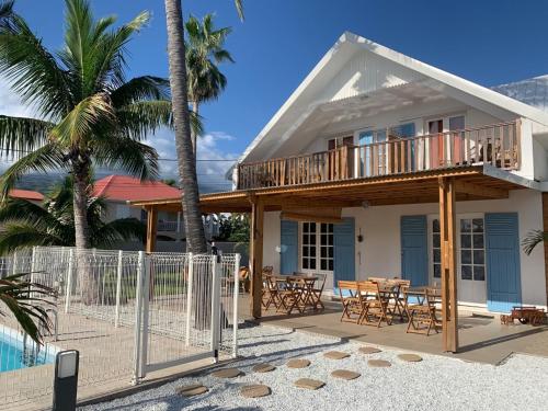 a house on the beach with a deck and tables at LE NID TROPICAL in Étang-Salé les Bains