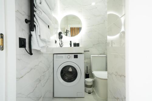 a white bathroom with a washing machine and a toilet at MYFREEDOM Апартаменти метро Почайна, Оболонь in Kyiv