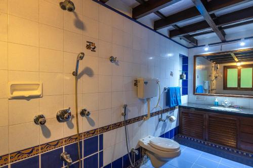 a bathroom with a toilet and a sink and a mirror at SaffronStays Alma Grove, Kashid in Kashid