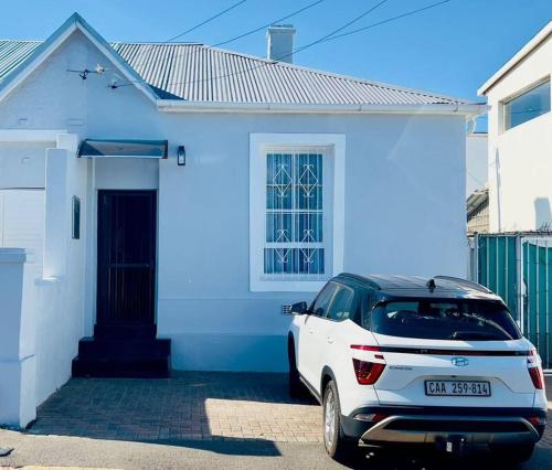 un coche blanco estacionado frente a una casa blanca en Modern Victorian 4 bedroom home in trendy Observatory., en Ciudad del Cabo