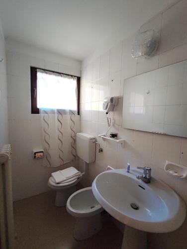 a bathroom with a sink and a toilet and a window at Hotel TEA DOLOMITI - Lago di Alleghe - Monte Civetta in Alleghe