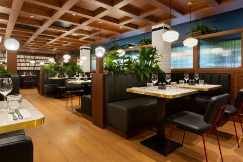 un restaurante con mesas, sillas y plantas en RockyPop Grenoble Hotel, en Grenoble