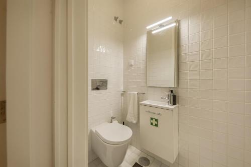 a white bathroom with a toilet and a mirror at Caju Deluxe Apartment in Aveiro