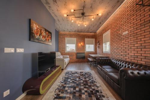 a living room with leather furniture and a brick wall at Caju Deluxe Apartment in Aveiro