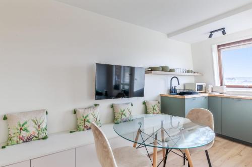 uma cozinha com uma mesa de vidro e cadeiras em Brand new studio with sea view in the Deauville port - Welkeys em Deauville