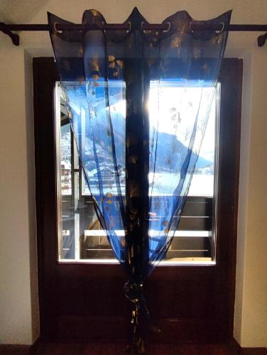 a wooden door with a window with a blue curtain at Hotel TEA DOLOMITI - Lago di Alleghe - Monte Civetta in Alleghe