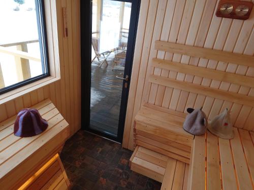 una sauna con una puerta y dos zapatos sentados en un banco en MĖTA en Birštonas
