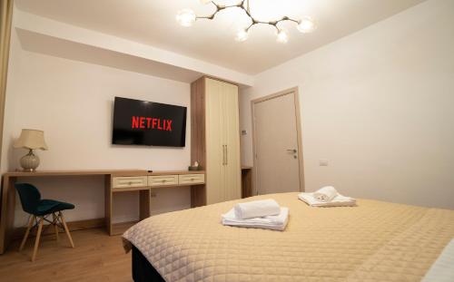 a bedroom with a bed and a desk and a tv at Coban Residence Apartments in Braşov