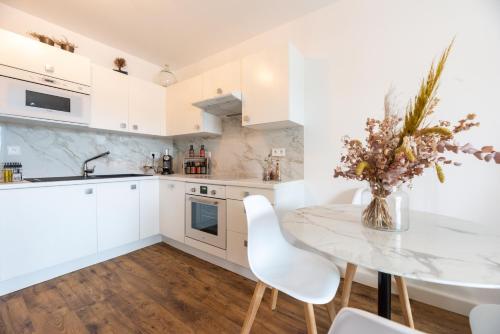 une cuisine avec des armoires blanches et une table et des chaises dans l'établissement Occi, à LʼÎle-Rousse