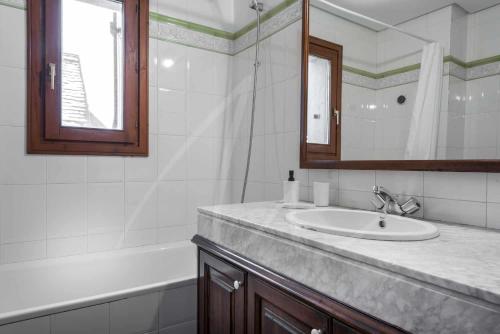 y baño con lavabo, espejo y bañera. en Tanau 1700 by SeaMount Rentals, en Naut Aran (Alto Arán)