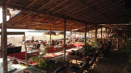 Un grupo de personas sentadas en sillas en la playa. en Casa fiesta Sea front beach huts, en Patnem