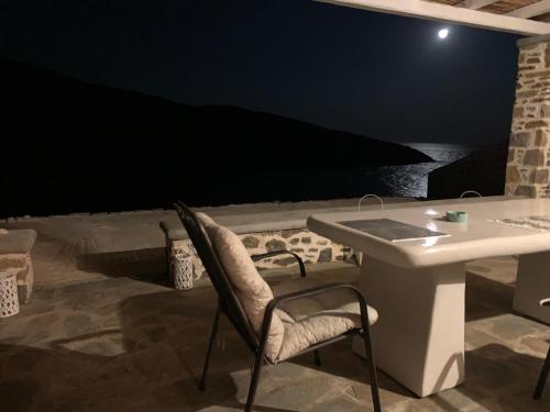 uma mesa e uma cadeira num pátio à noite em Kythnos Beach house em Kythnos