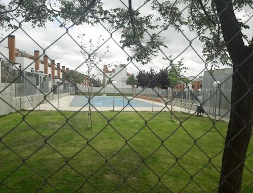 una valla de cadena con una piscina detrás de ella en Chalet Familiar Jardín a 15 min centro y Warner, en Rivas-Vaciamadrid