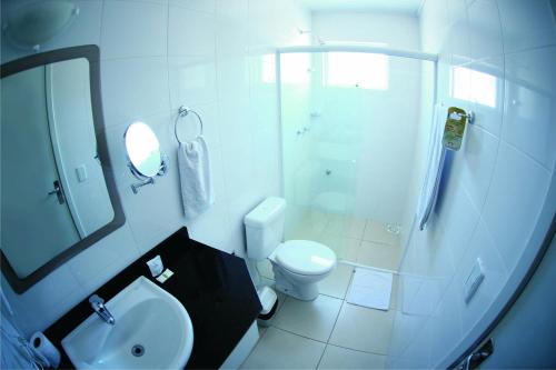 a white bathroom with a toilet and a sink at Hotel Bartz in Camaquã