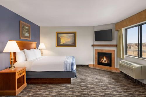 拉勒米的住宿－拉勒米阿美瑞辛旅館及套房，酒店客房配有一张床和一个壁炉。