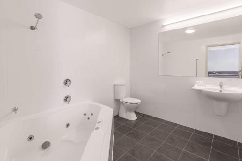 a bathroom with a tub and a toilet and a sink at Travelodge Hotel Hobart Airport in Cambridge