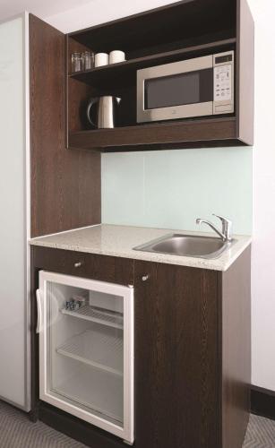 a kitchen with a sink and a microwave at Travelodge Hotel Hobart in Hobart
