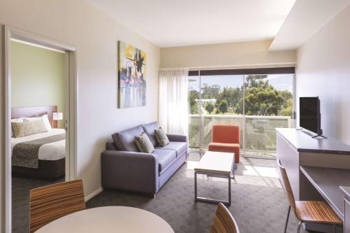 um quarto de hotel com um sofá e uma cama e uma janela em Travelodge Hotel Hobart Airport em Cambridge