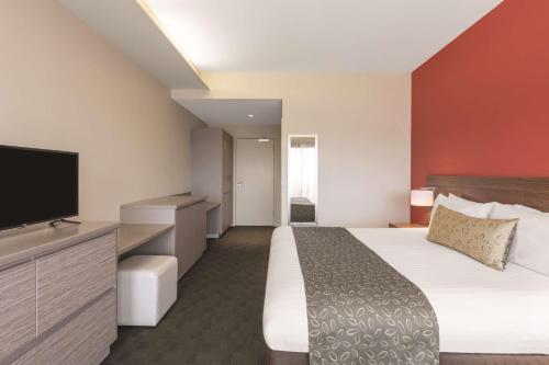 a hotel room with a bed and a flat screen tv at Travelodge Hotel Hobart Airport in Cambridge