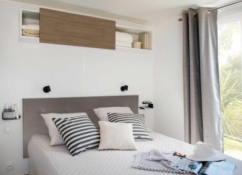 a bedroom with a bed with striped pillows and a window at Camping Village Mar y Sierra in San Costanzo