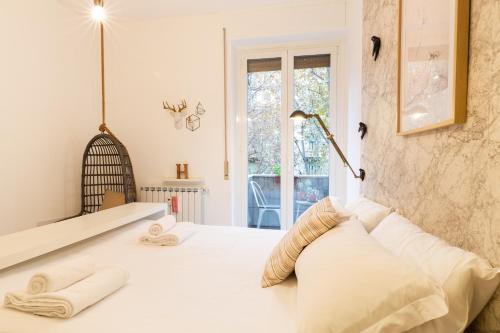Schlafzimmer mit einem Bett mit weißer Bettwäsche und einem Fenster in der Unterkunft GoodVibesHome in Mailand