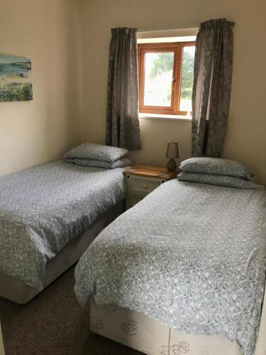 2 camas individuales en un dormitorio con ventana en Court Farm Holiday Bungalows Ltd, en Watchet