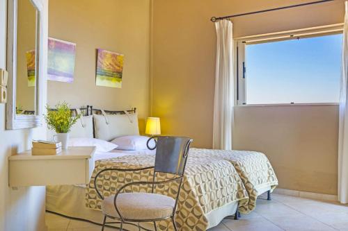 um quarto com uma cama, uma cadeira e uma janela em Villa Agriada by Villa Plus em Spathíon