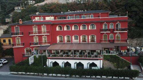 a red building with a restaurant in front of it at Hotel Merano in Brenzone sul Garda