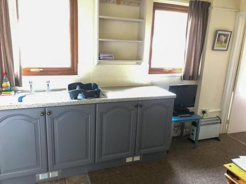 a kitchen with a sink and a desk with a computer at Court Farm Holiday Bungalows Ltd in Watchet