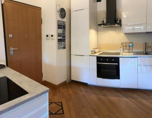 een keuken met witte kasten en een zwarte oven bij Favoloso appartamento Roma con giardino in Rome