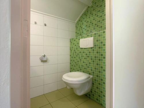 a green tiled bathroom with a toilet in it at Spaanse Galeienstraat 75 in Retranchement