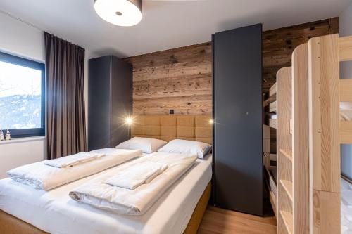 a bedroom with two beds and a wooden wall at Hideaway Dachstein West by ALPS RESORTS in Sankt Martin am Tennengebirge