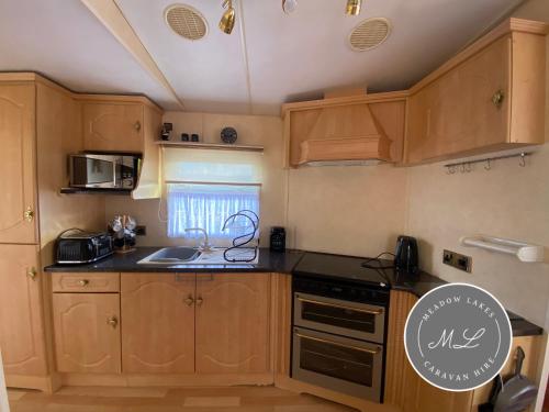 a kitchen with wooden cabinets and a sink at Seaview - 145 - Ingoldmells in Ingoldmells