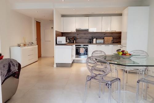 une cuisine avec des armoires blanches et une table et des chaises dans l'établissement Sublime Apartment Center Croisette LIVE IN Moliere, à Cannes