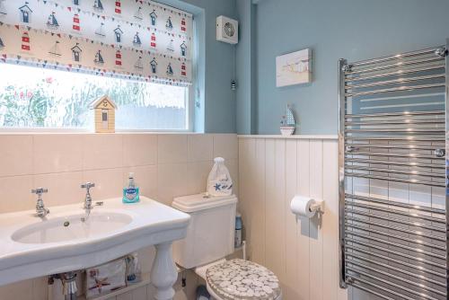 a bathroom with a sink and a toilet and a window at Fishermans Cottage in Aldeburgh
