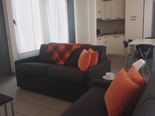 a living room with a black couch with orange pillows at Appartamenti tra Lago e Montagna CASA IDEALE LECCO in Lecco