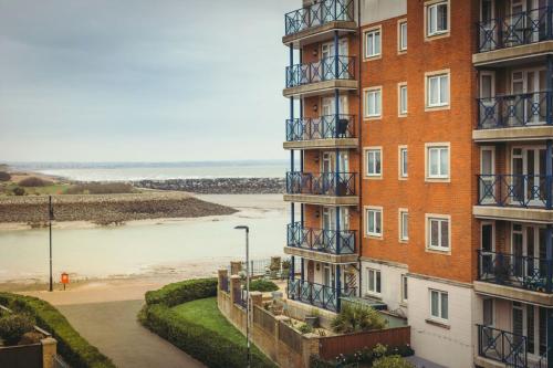 a tall brick building with balconies and a beach at Sovereign Sunrise near to beach in Eastbourne