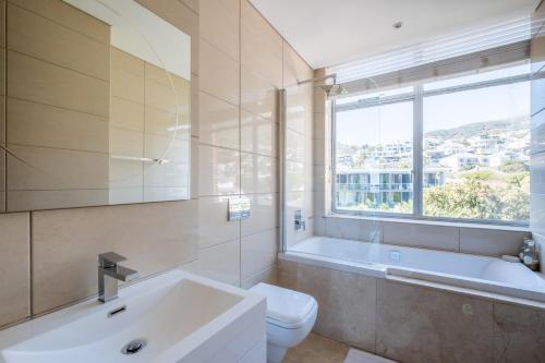 a bathroom with a tub and a toilet and a sink at Beach Vista by Totalstay in Cape Town