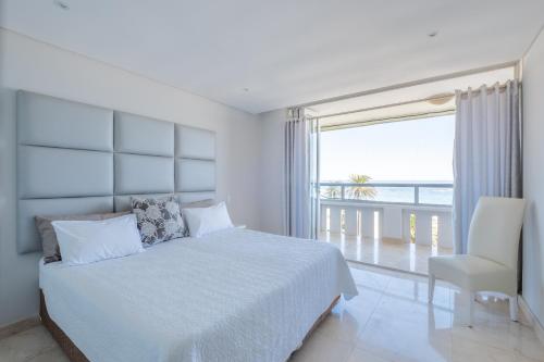a white bedroom with a bed and a large window at Beach Vista by Totalstay in Cape Town