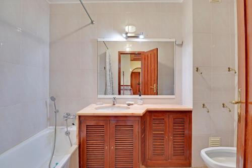 een badkamer met een wastafel, een bad en een spiegel bij Monte Gordo Beachview 2 by Homing in Monte Gordo