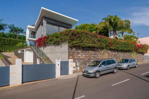 two cars parked in front of a building with flowers at Villa das Quebradas by An Island Apart in Funchal