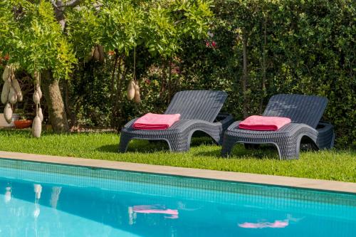 two chairs with red cushions next to a swimming pool at Villa das Quebradas by An Island Apart in Funchal