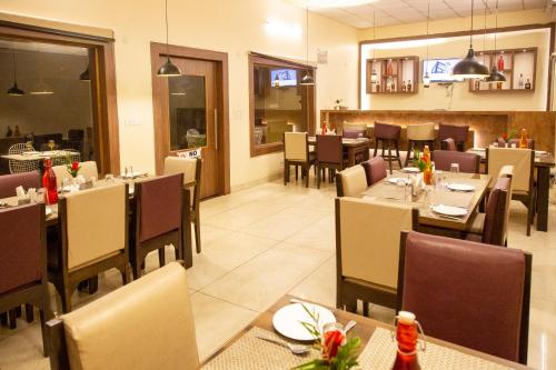 uma sala de jantar com mesas e cadeiras num restaurante em Clarks Inn Dudhwa em Paliā Kalān