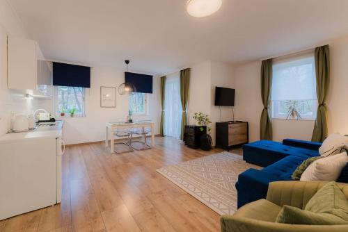 uma sala de estar com um sofá azul e uma cozinha em Csendes, modern, otthonos társasházi lakás em Zalacsány