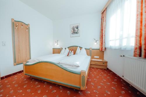 a bedroom with a bed and a large window at Dandler - Zimmer und Ferienwohnungen in Fieberbrunn