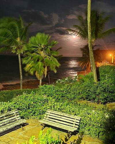 two park benches in front of the ocean at night at Barbanera Club & Hotel de Charme in Caucaia