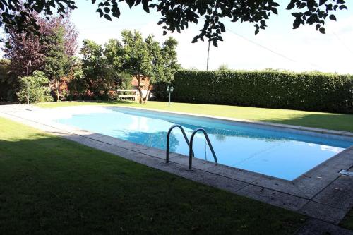 a swimming pool with two metal rails in the grass at Casa dos três rapazes in Monte Córdova